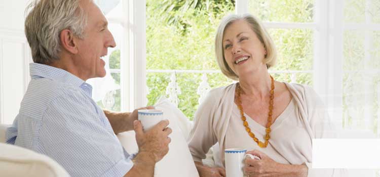 Puede ver una mujer y un hombre tomando un té en el sofá. Los dos se entretienen de forma animada.